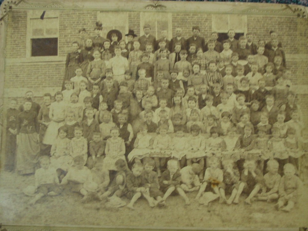 Picture of the school with Children in front of it.